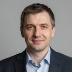 Портрет уверенного российского бизнесмена с дружелюбным взглядом на нейтральном размытом фоне студии